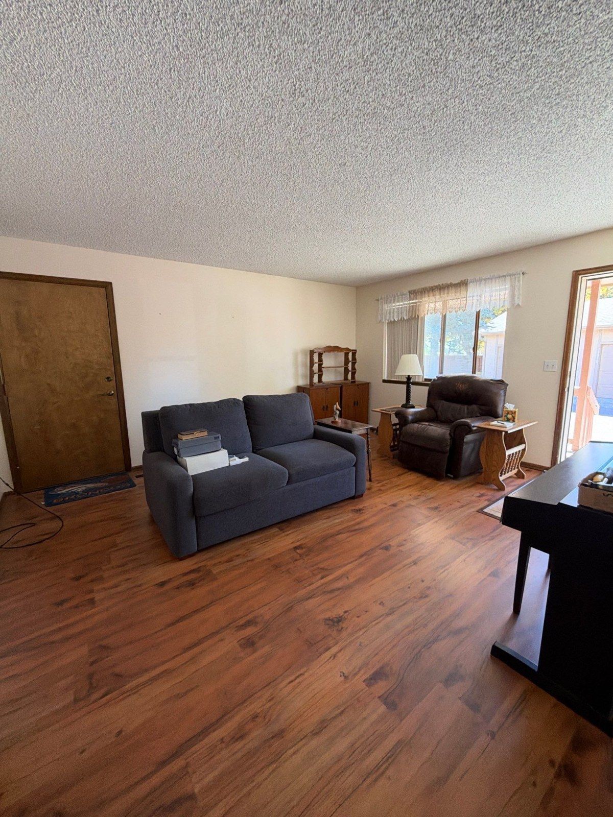 Existing living room with furniture, wood flooring and a textured ceiling at the Colorado Springs project