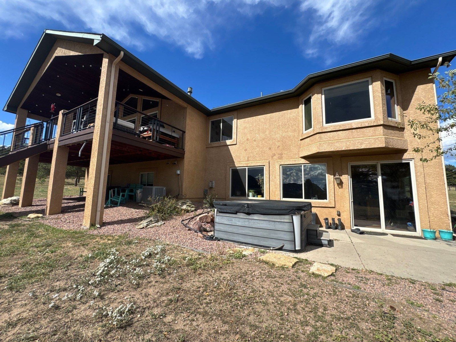 Existing rear stucco walls, covered porch ceiling and patio beside an elevated deck in the same Larkspur project