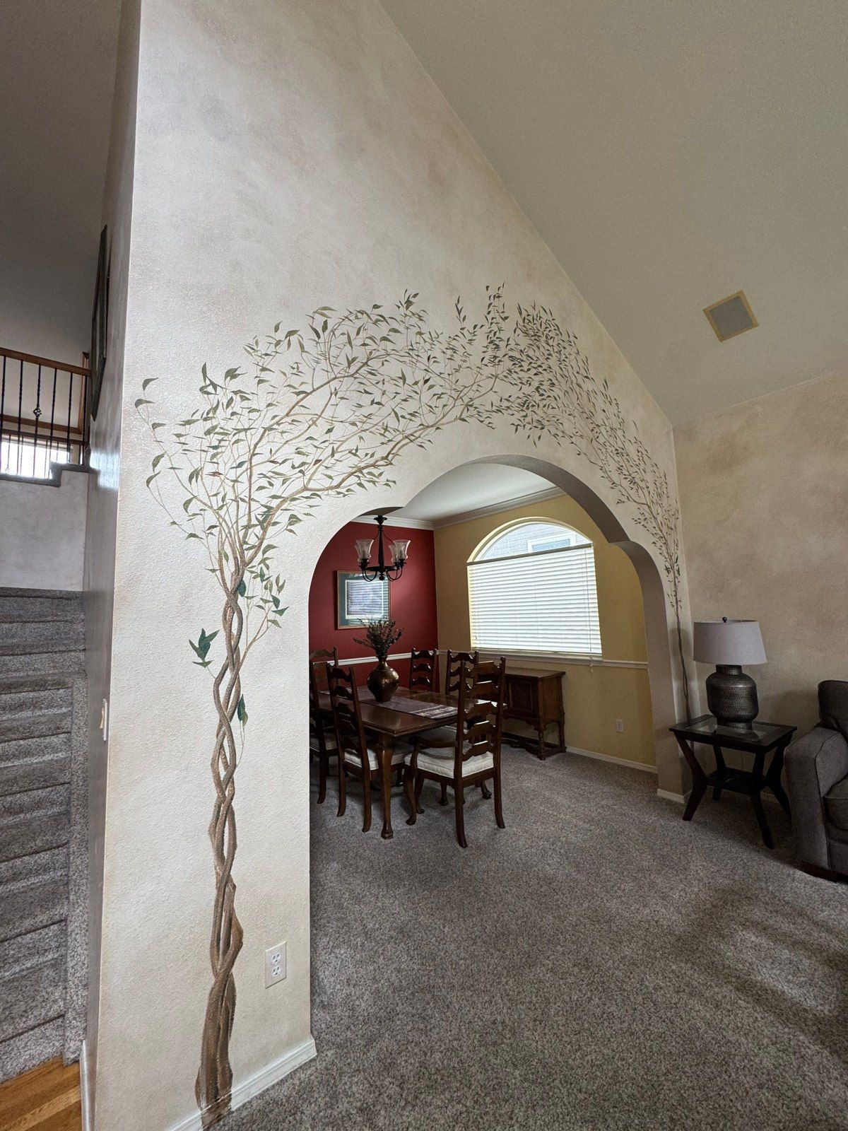 Painted mural around an arched interior opening with a view into an adjoining room