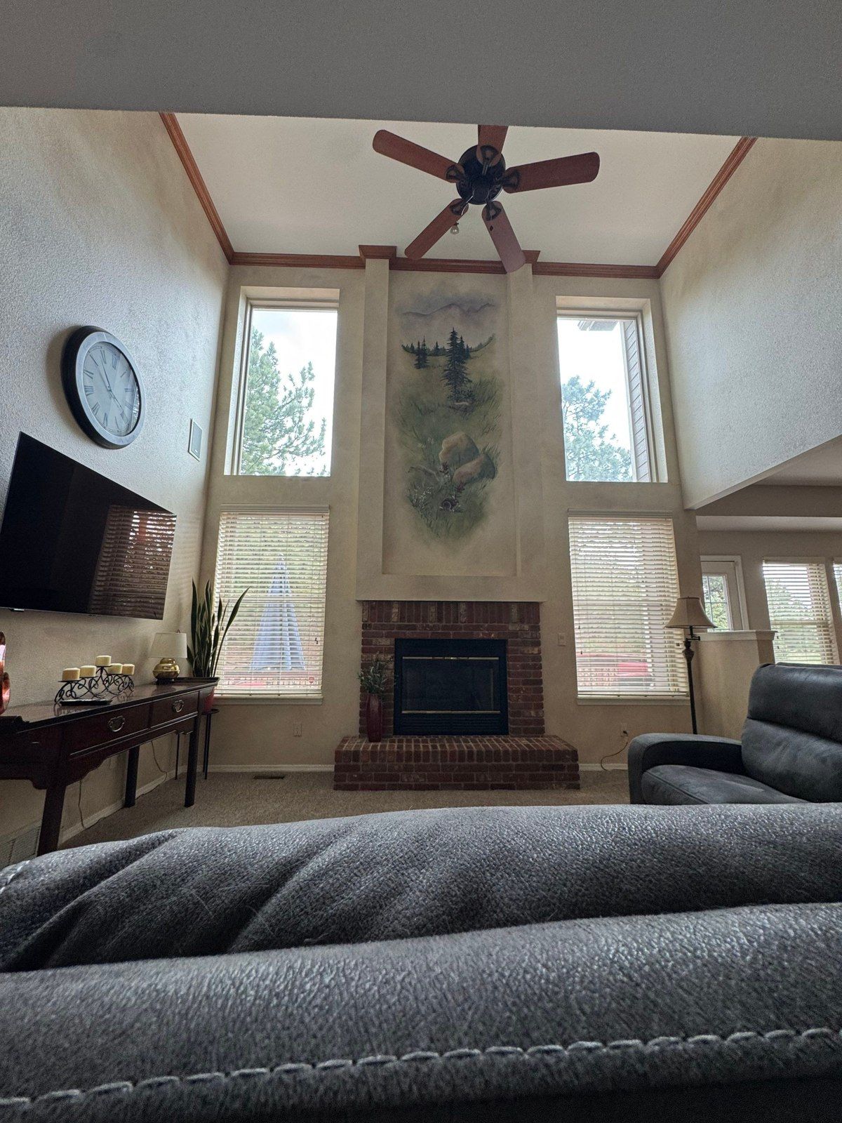 Existing mural-covered tall wall above a fireplace between windows in a Colorado Springs interior estimate