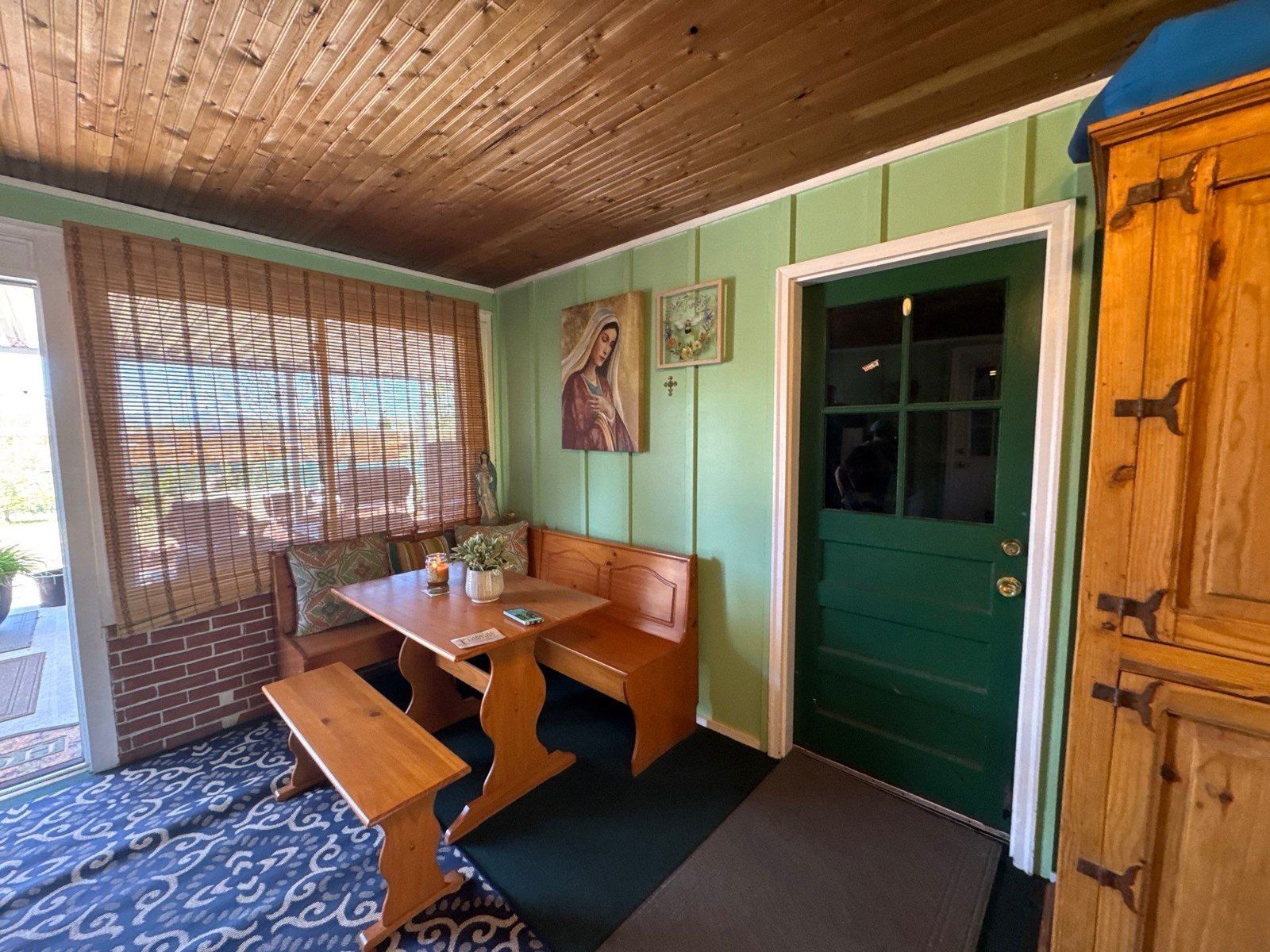 Painted wall panels beside wide windows, a doorway and a retained stained wood ceiling