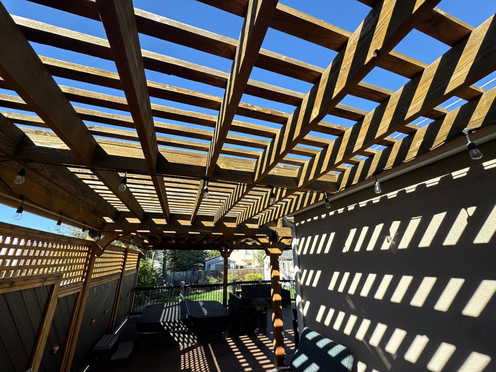 Underside view of the same pergola showing overhead slats, beams and neighboring surfaces
