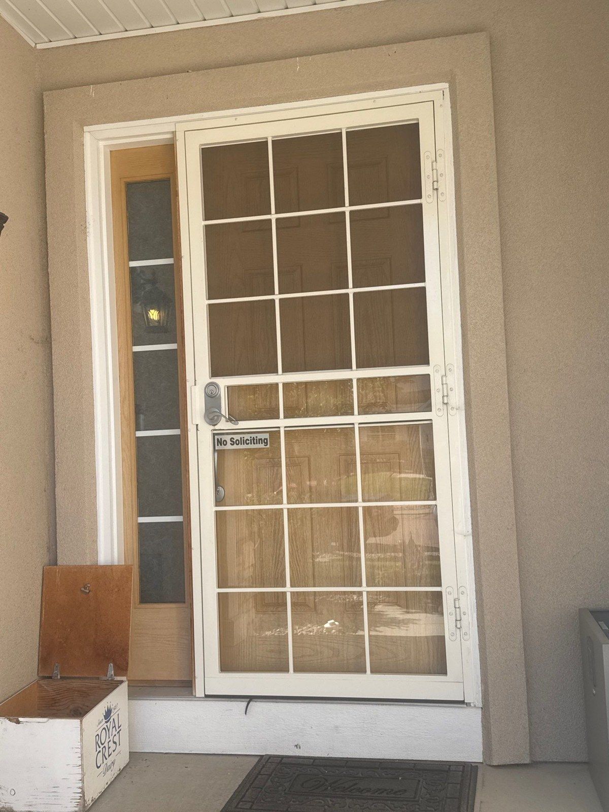 Wood front door and sidelight behind a white outer door at the same Colorado Springs property