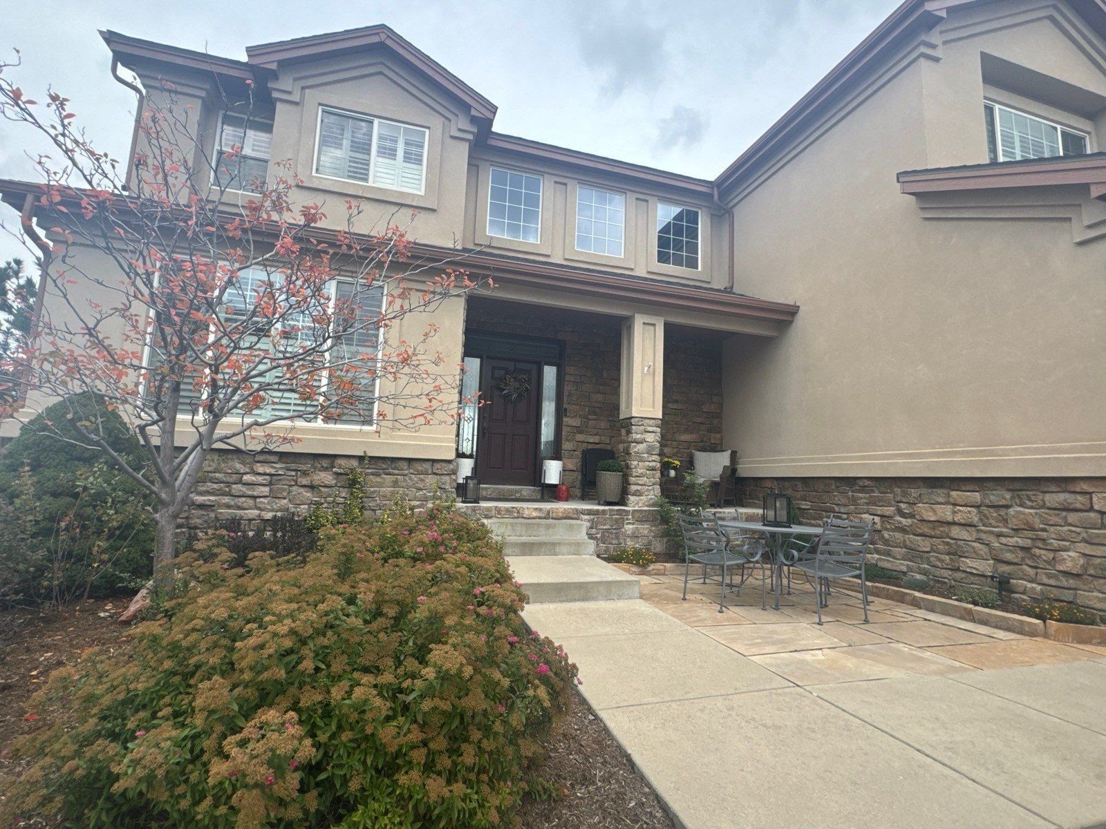 Existing Colorado Springs facade with stucco, front stone and dark trim in the same exterior estimate