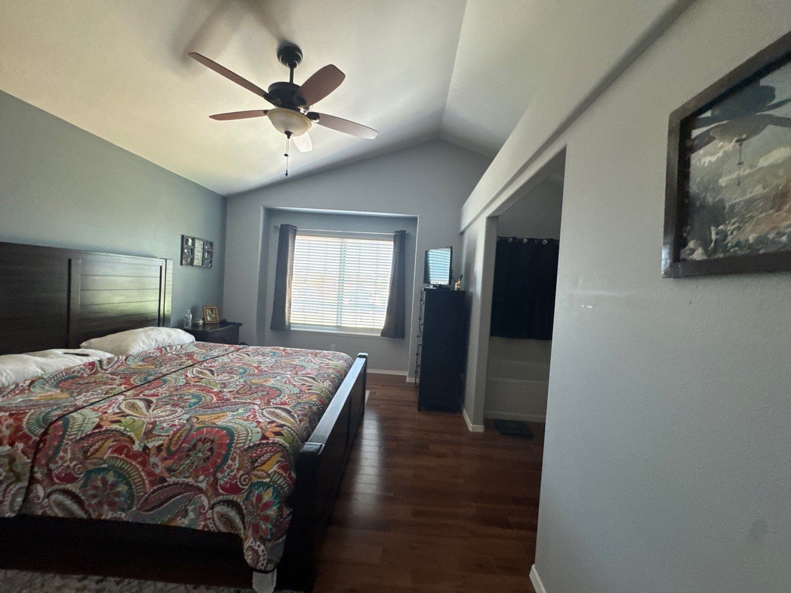 Existing bedroom with bed, ceiling fan, painted walls, light trim and retained flooring in a Colorado Springs estimate
