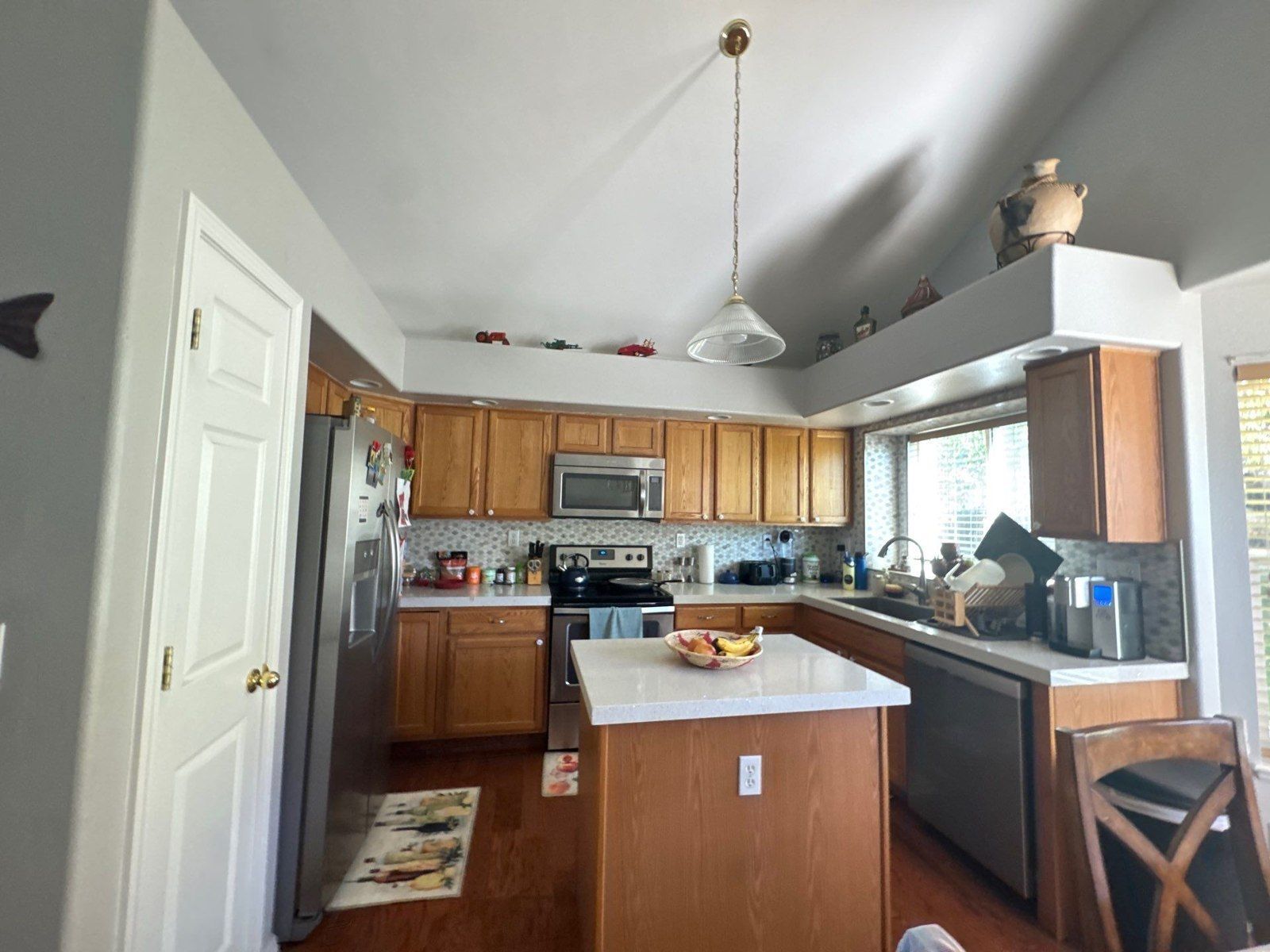 Existing kitchen with wood cabinets, island and wall and ceiling surfaces in a Colorado Springs interior painting proposal