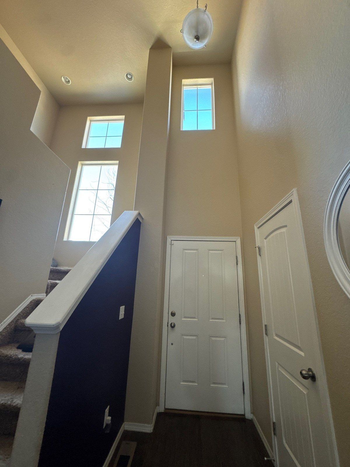 Tall entryway with existing walls, upper windows, stair railing and white doors in a Colorado Springs interior estimate