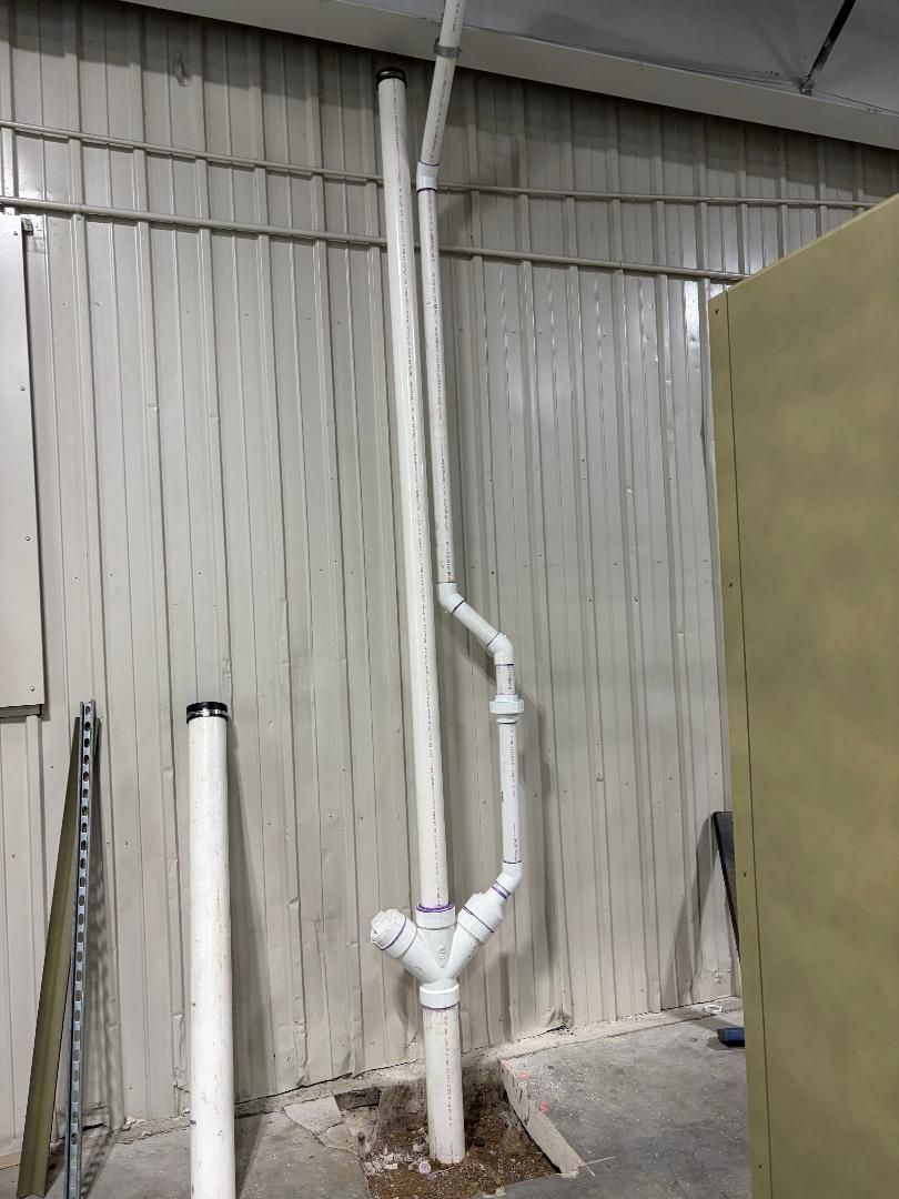 White PVC pipes against a corrugated metal wall in an industrial setting