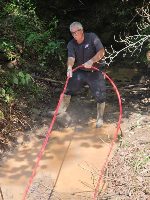 Man standing in muddy water holding red ropes on a forest path