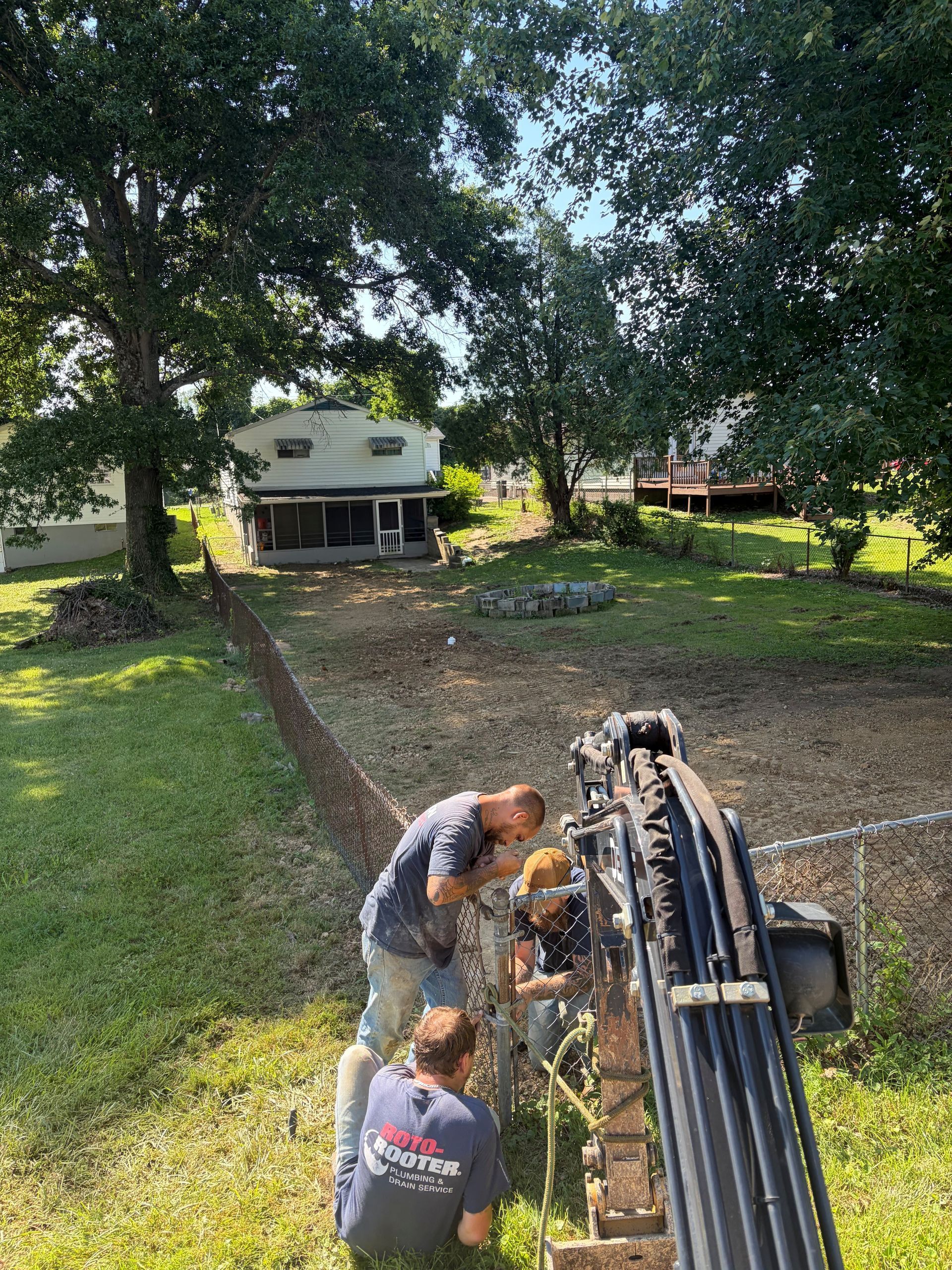 Worker and large drill rig on a grassy yard with a house in the background