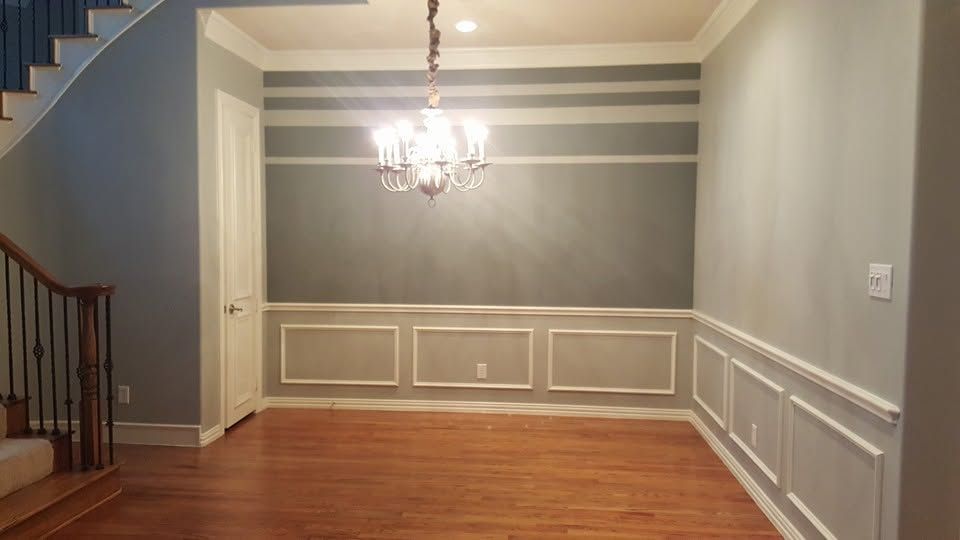 Empty dining room with gray walls, white trim, hardwood floor, and a chandelier