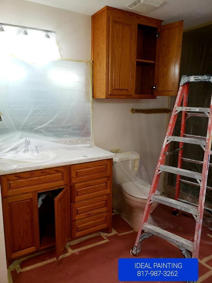 Kitchen under renovation with cabinets, covered countertop, and red ladder against the wall