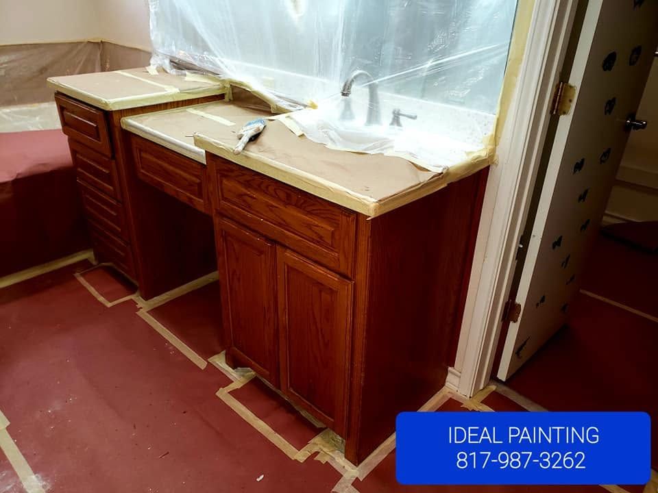 Two bathroom vanities with sinks, partially covered for painting, in a room with red floor protection