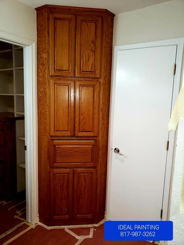 Tall wooden cabinet beside a white door in a hallway, with a blue “Deal Painting” label at the bottom.