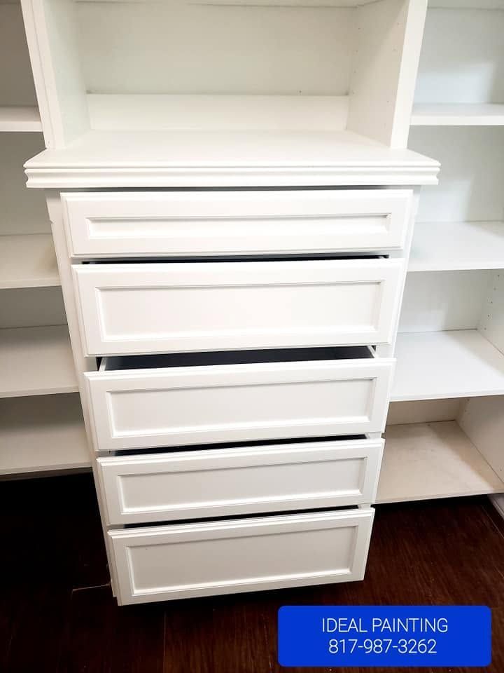 White built-in closet with six drawers and open shelves, plus a small blue Ideal Painting sign at bottom right