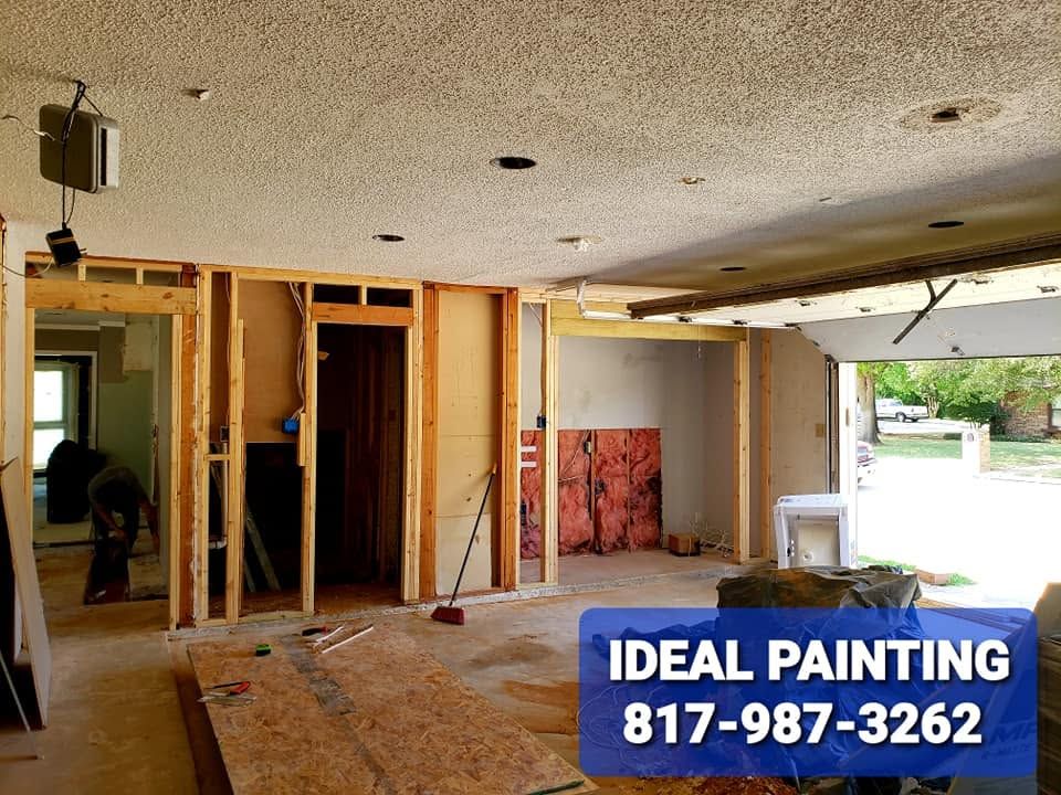 Partially demolished room interior with exposed framing and a painting company sign in the foreground