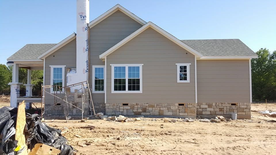 New beige house under construction with stone foundation and clear blue sky