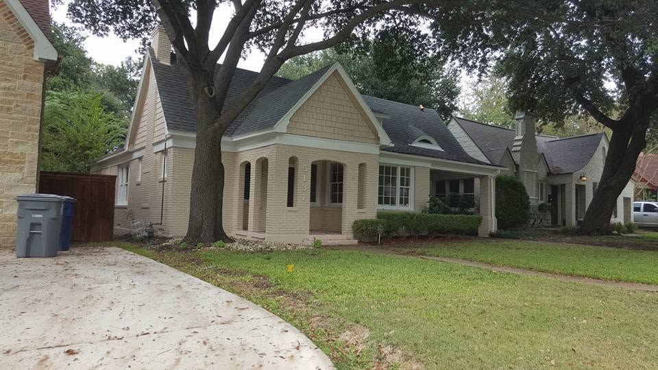 Suburban house with beige siding, front lawn, trees, and a curved driveway