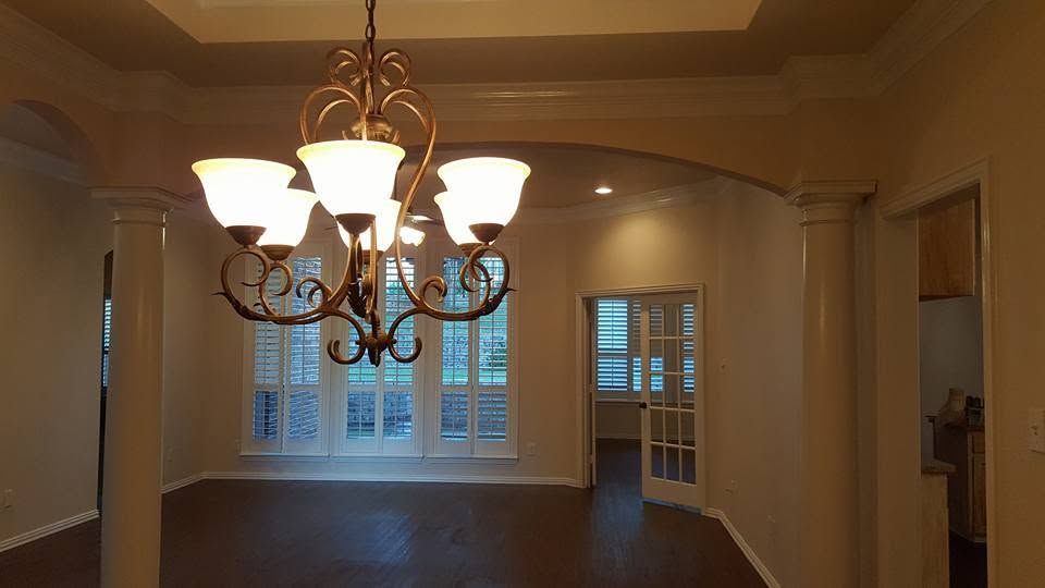 Dining room with a lit chandelier, tray ceiling, and windows at the far wall.