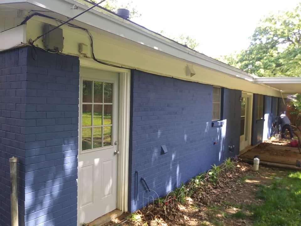 Blue house exterior with white door and windows, side yard and porch area under a slanted roof