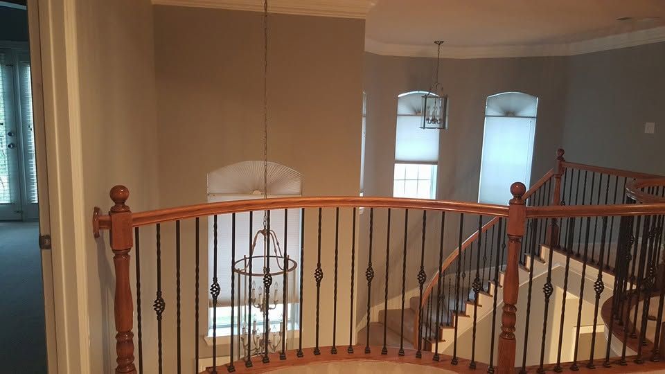 Interior balcony with wooden railing overlooking a foyer and staircase