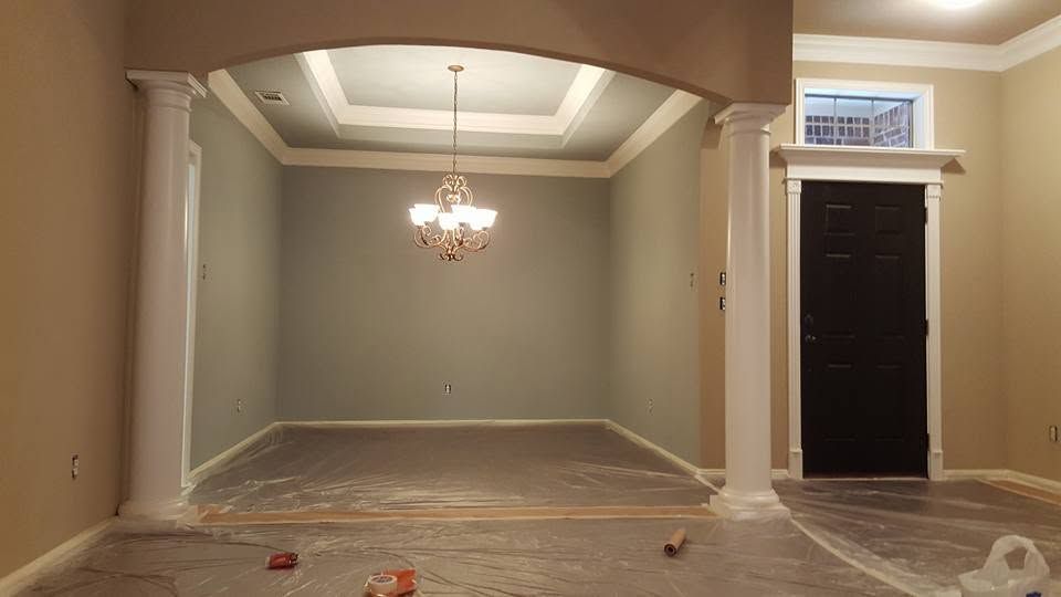Empty dining room with beige walls, chandelier, and dark front door; floor covered in protective plastic during renovation