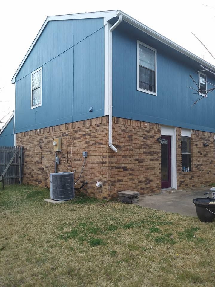 Blue and brick two-story house with a small yard and an air conditioner unit outside