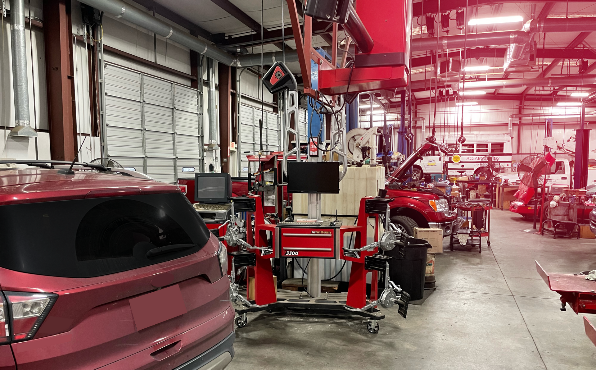 A red car is parked in a garage next to a machine. | Automotive Fleet Repair