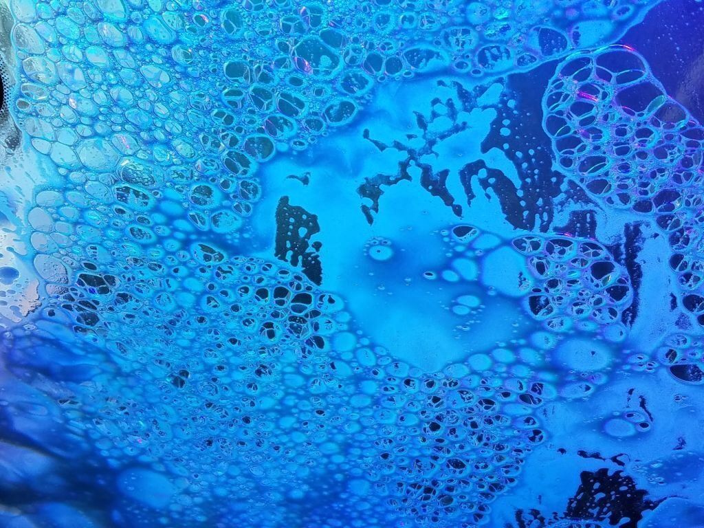 Photo of Bubbles on Car Window during car wash in blue lighting