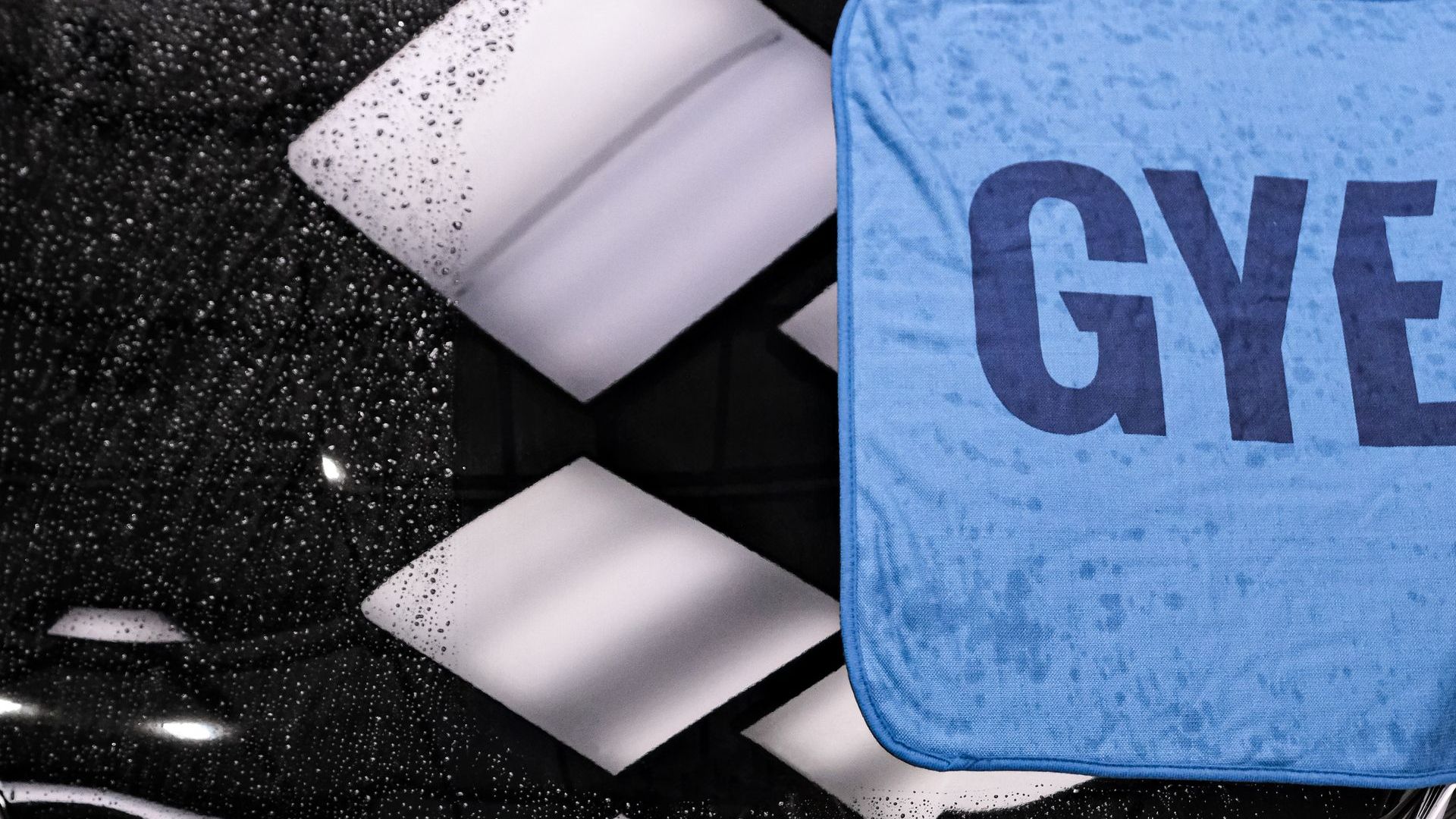 a bottle of towel wash is sitting on top of a pile of purple towels .