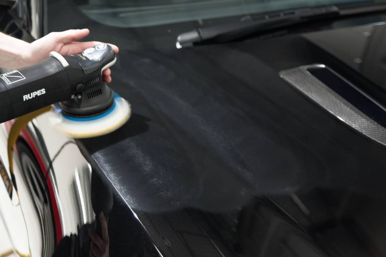 Polisher being used on black car for paint correction service