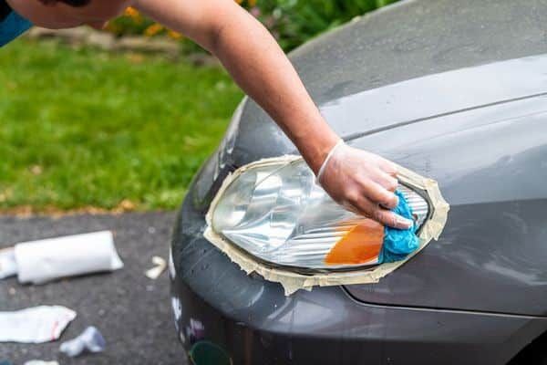 Grey car headlight being taped off for restoration