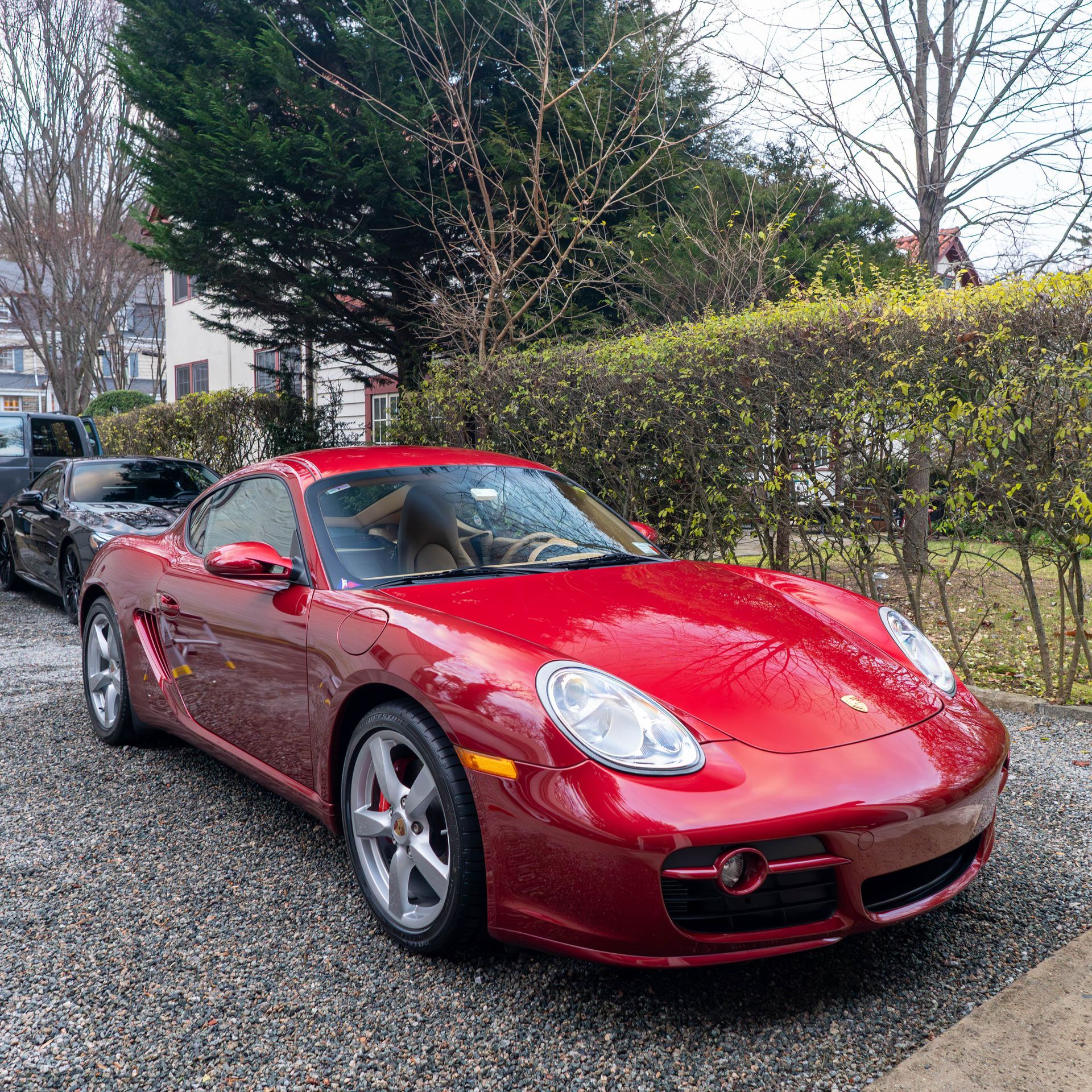 a red porsche cayman is parked in a gravel driveway .