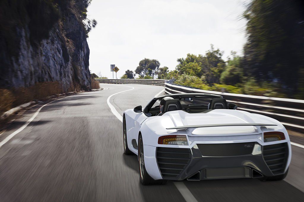 A white sports car is driving down a curvy road
