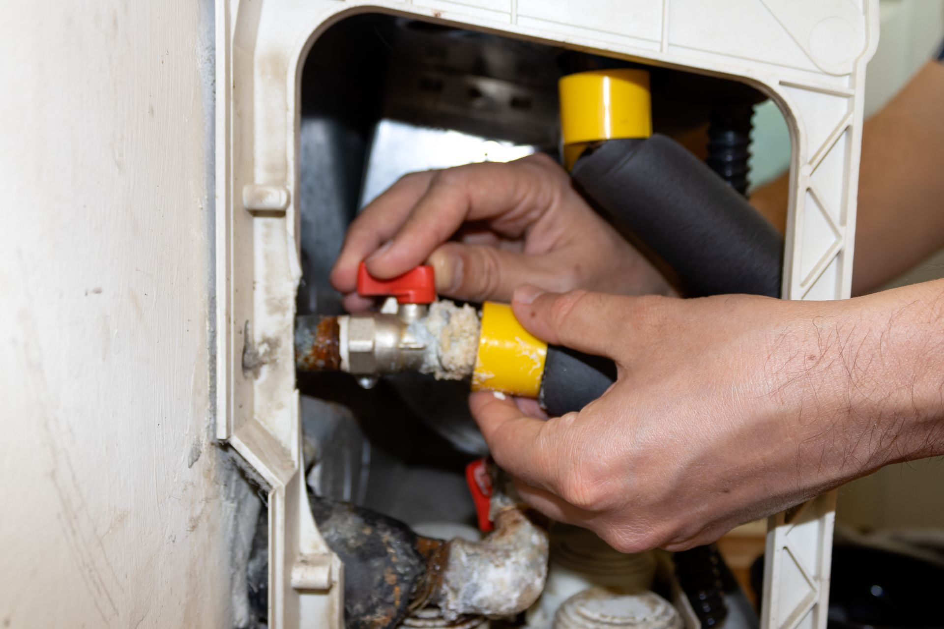 Hands tightening a gas valve and hose inside a utility cabinet Hands tightening a gas valve and hose inside a utility cabinet