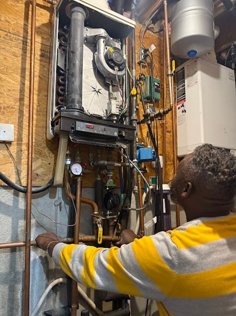 Technician inspecting a wall-mounted HVAC unit and pipes in a utility room