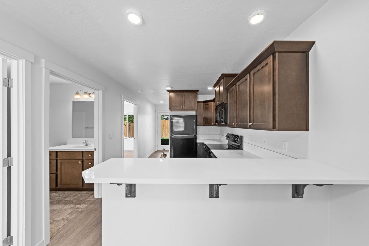 Bright modern kitchen with white island, dark wood cabinets, and stainless appliances