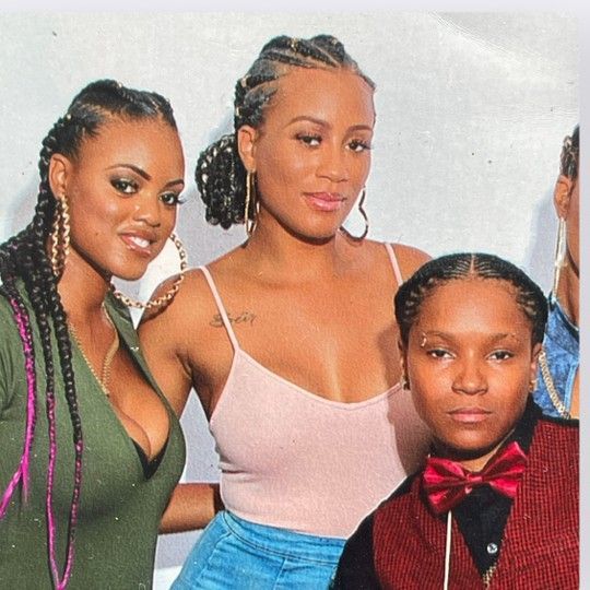 Three individuals posing together; one wears a green top, one a pink tank top, and one a red vest with a bowtie.