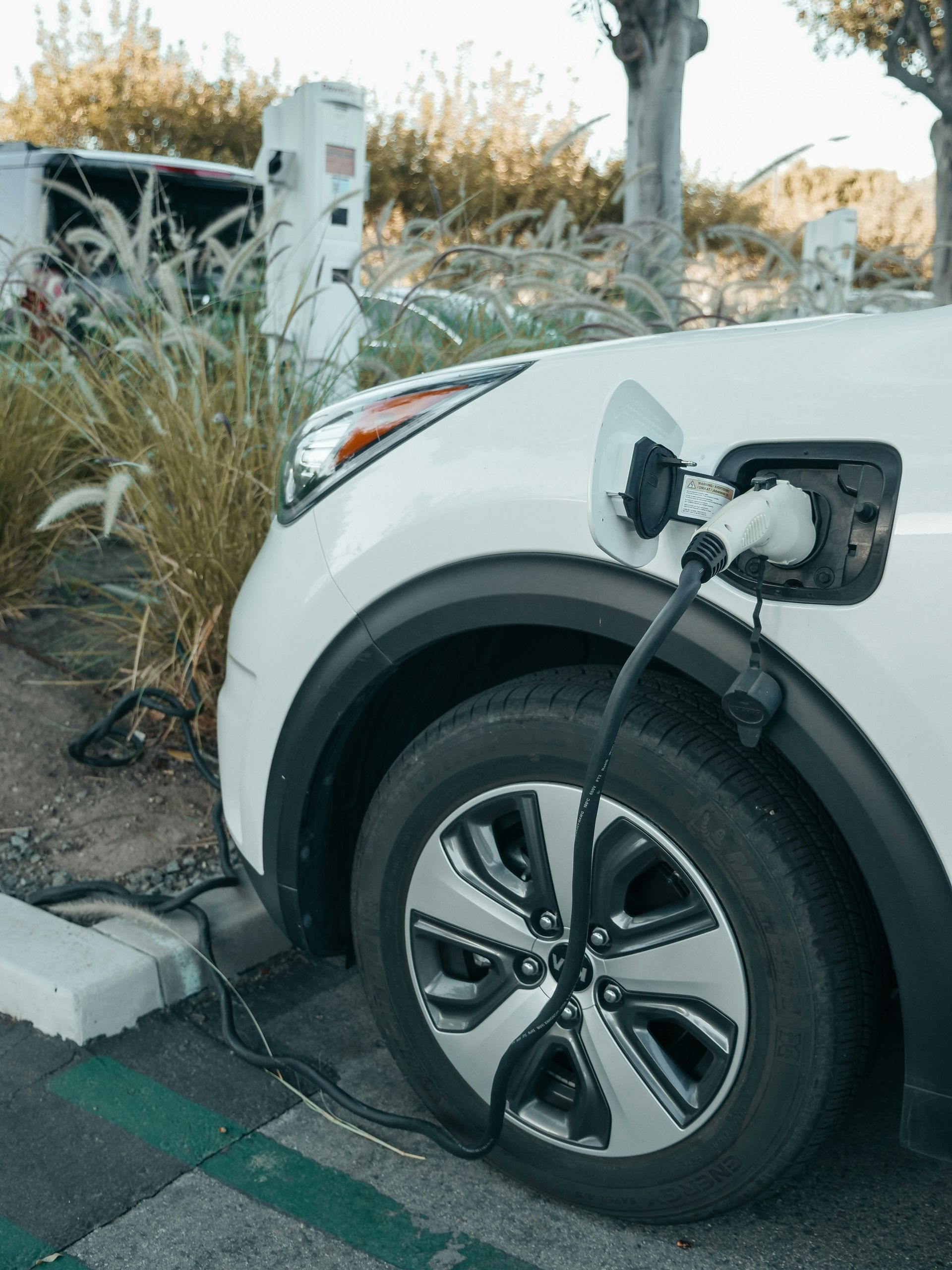 A white electric car is being charged at a charging station.