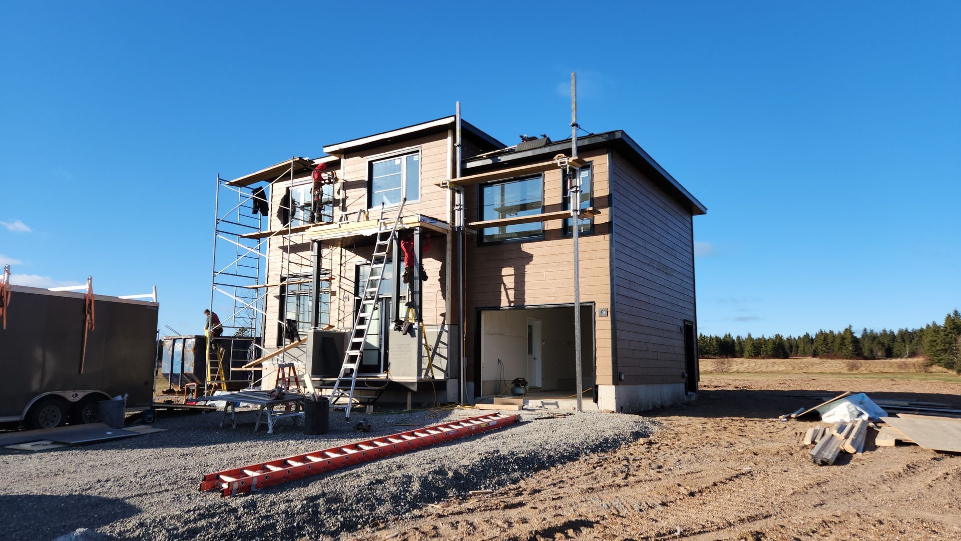 Une maison est en construction au milieu d’un champ de terre.