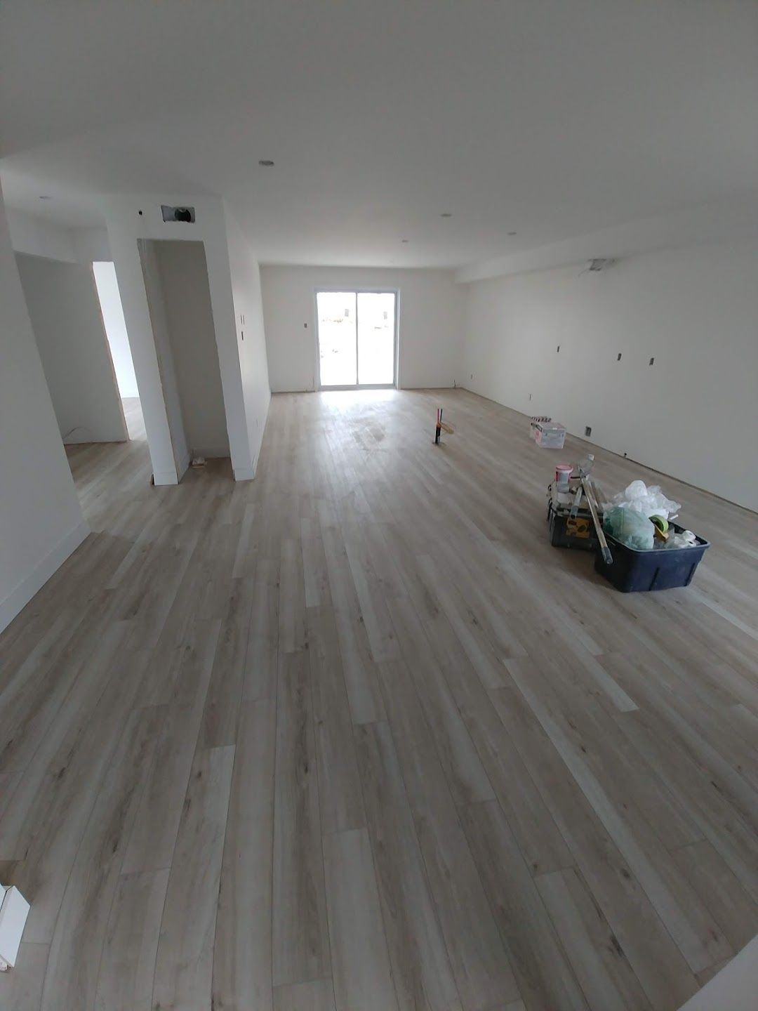 Une grande pièce avec du parquet et des murs blancs.