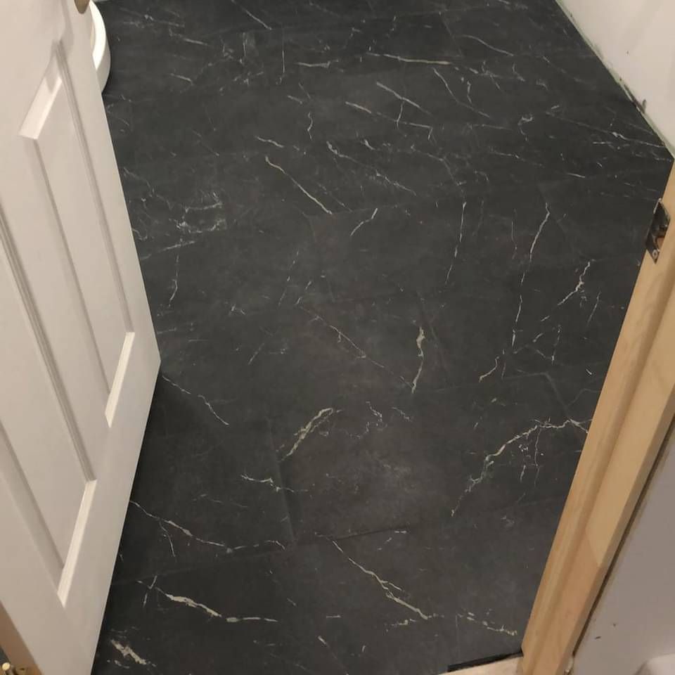 Un sol en marbre noir dans une salle de bain à côté d'une porte