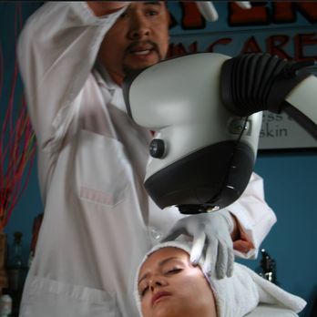 A man is using a microscope on a woman 's face