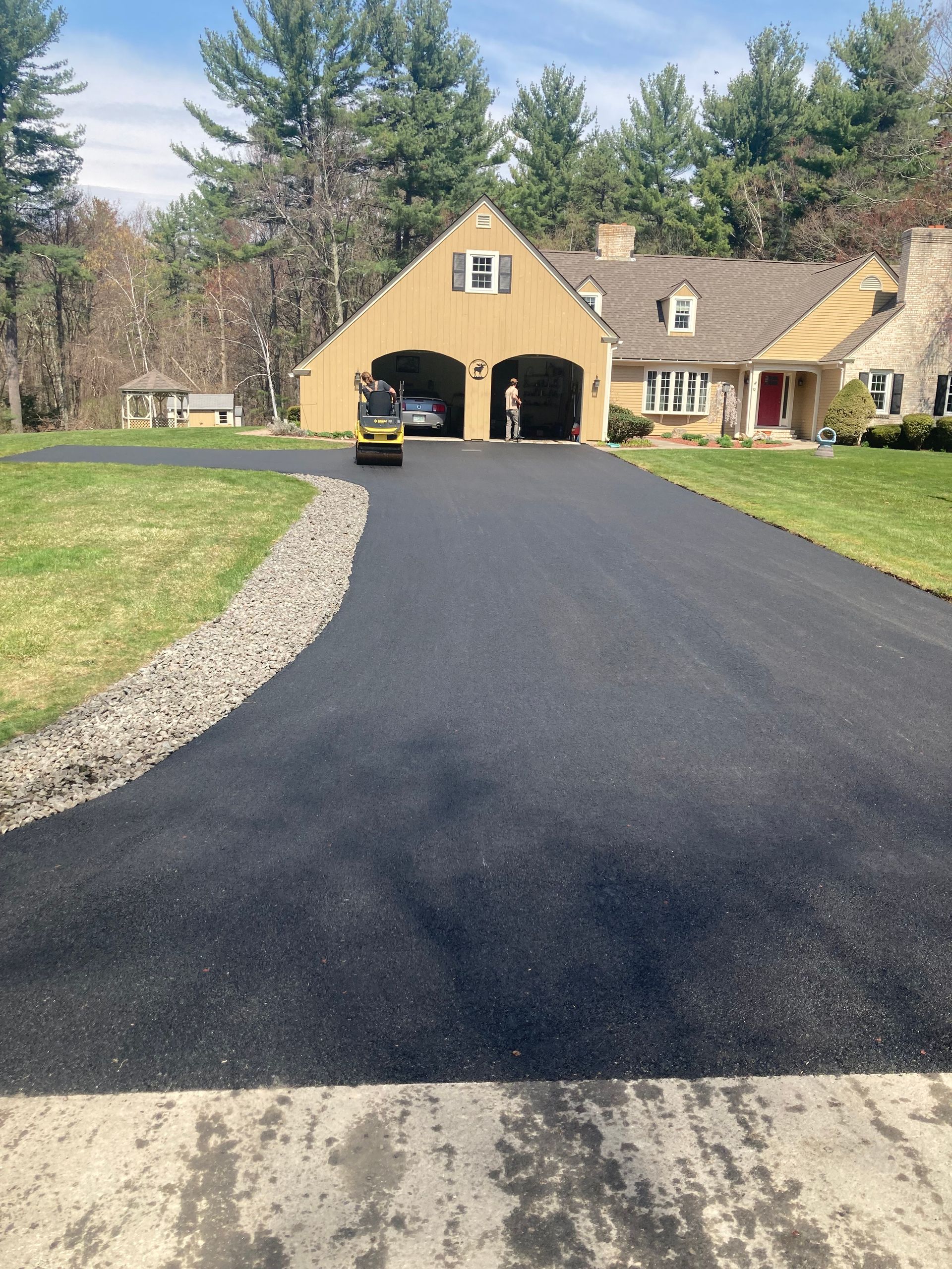 A driveway with a yellow house in the background