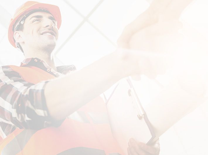 A person wearing a hard hat and high-visibility vest shaking hands with someone while holding a clipboard.