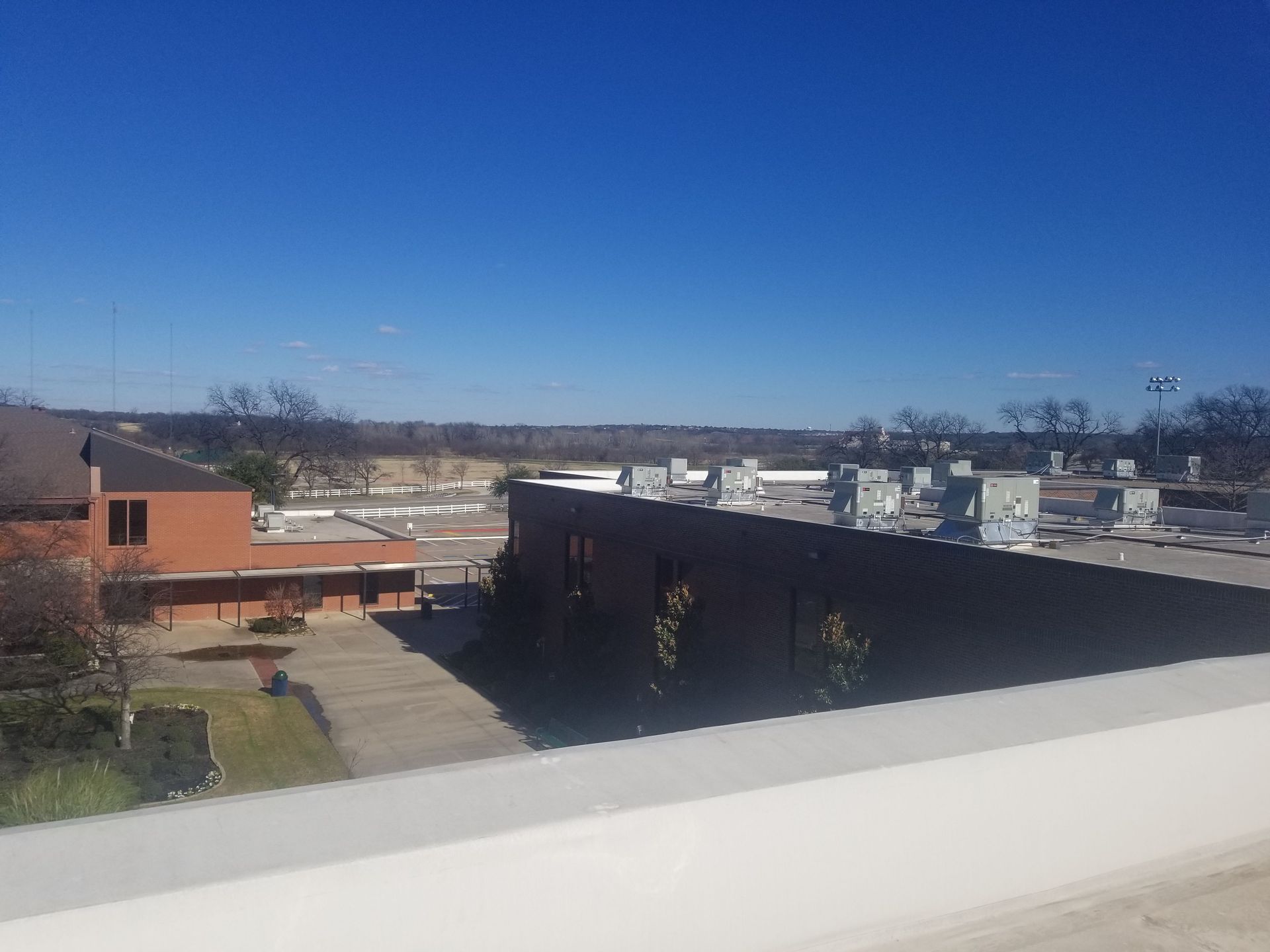 View from a rooftop overlooking brown and tan commercial buildings under a clear blue sky.
