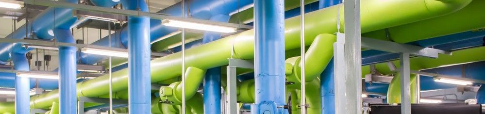 A network of bright lime-green and blue industrial pipes running through a utility or mechanical room.