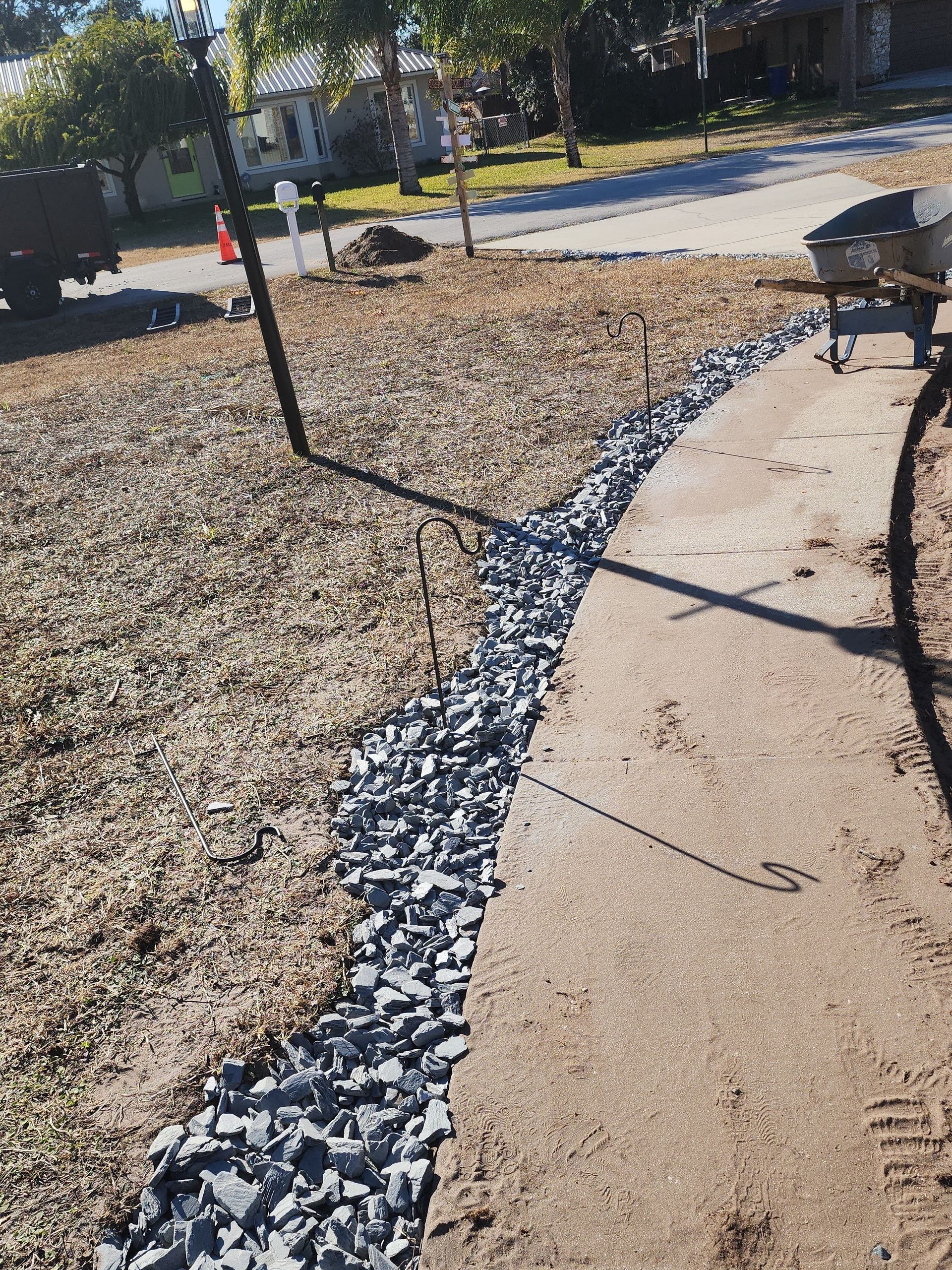 Curved walkway with a black drainage strip and mulch in a sunny park area
