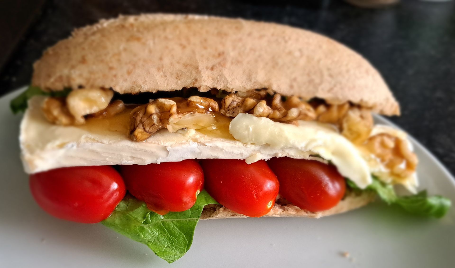 Sandwich met sla, cherrytomaatjes, kaas en noten op volkorenbrood