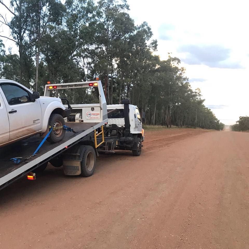 A White Truck is Being Towed by a Tow Truck on a Dirt Road — Cape York Towing & Transport in Pormpuraaw, QLD